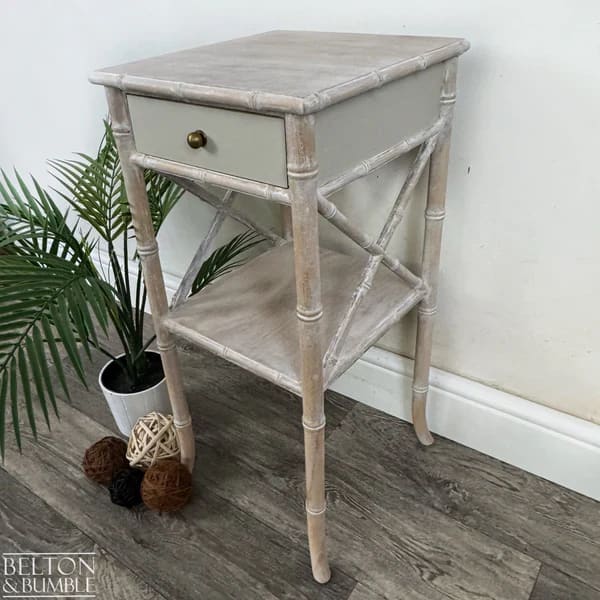 Side profile of faux bamboo bedside table with slender legs and cross-stretcher support
