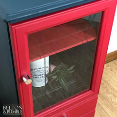 Close-up of etched glass door on blue and red hand painted drinks cabinet, highlighting vintage detail