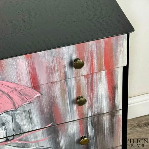 Close-up of antique-style brass knobs on jet black hand-painted mid-century chest of drawers