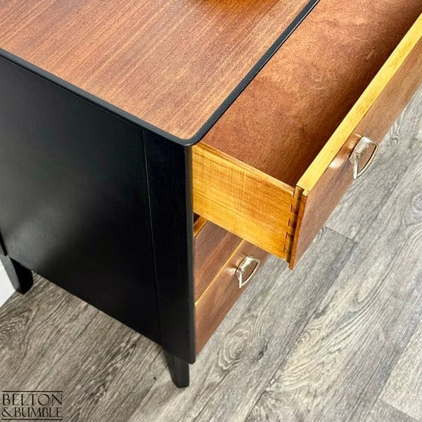 Detail of dovetailed drawers on mid-century modern chest of drawers with jet black body and teak fronts