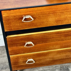 Detail of original hardware on mid-century modern chest of drawers with jet black body and teak fronts